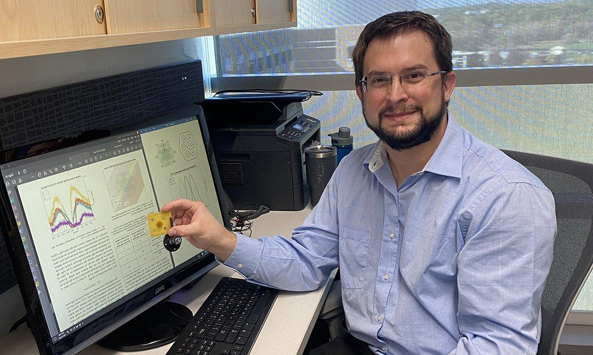 A man by a computer holding his research device