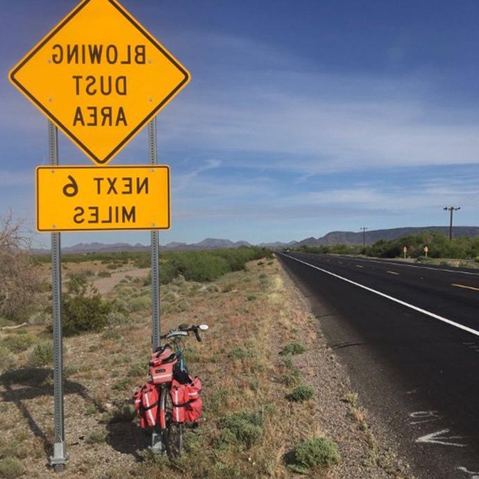 Bike and road with road sign that states "Blowing dust area next 6 miles"