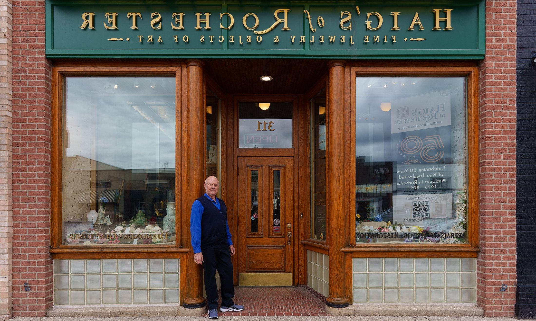 A man in front of his jewelry store with a sign that reads "Haig's of Rochester Fine Jewelry & Objects of Art"