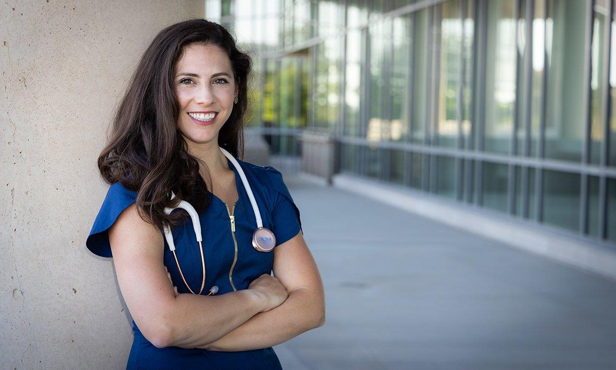 A woman in scrubs posing with her arms crossed.